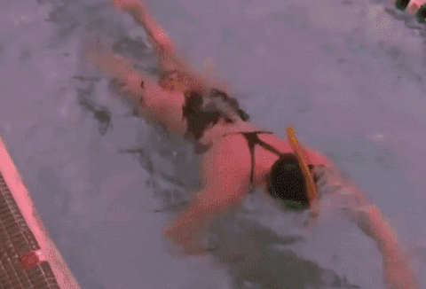 Une femme nage dans la piscine en portant d'élastique de nage piscine